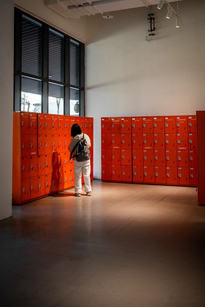 A person using red lockers in a modern, bright interior space with natural light.